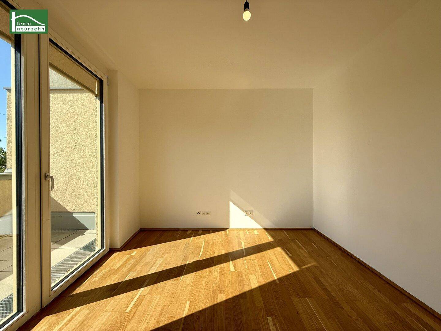 Heller Raumeck mit Parkettboden und großem Fenster, das viel Sonnenlicht hereinlässt.