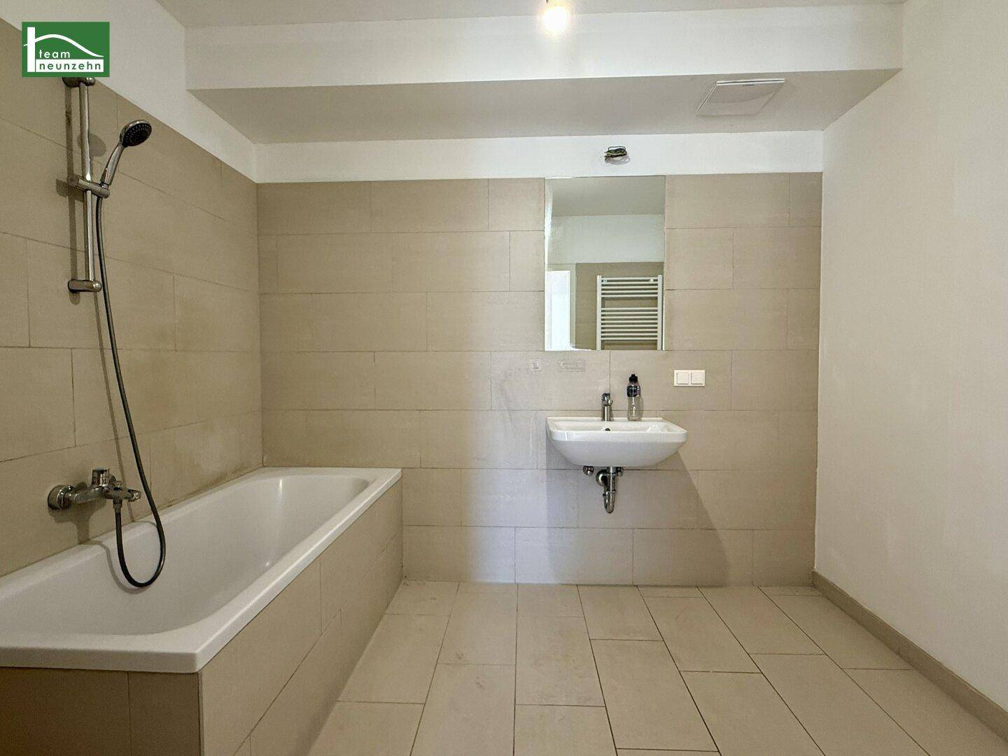 Modernes Badezimmer mit Badewanne, Einzelwaschbecken und hellen Fliesen.