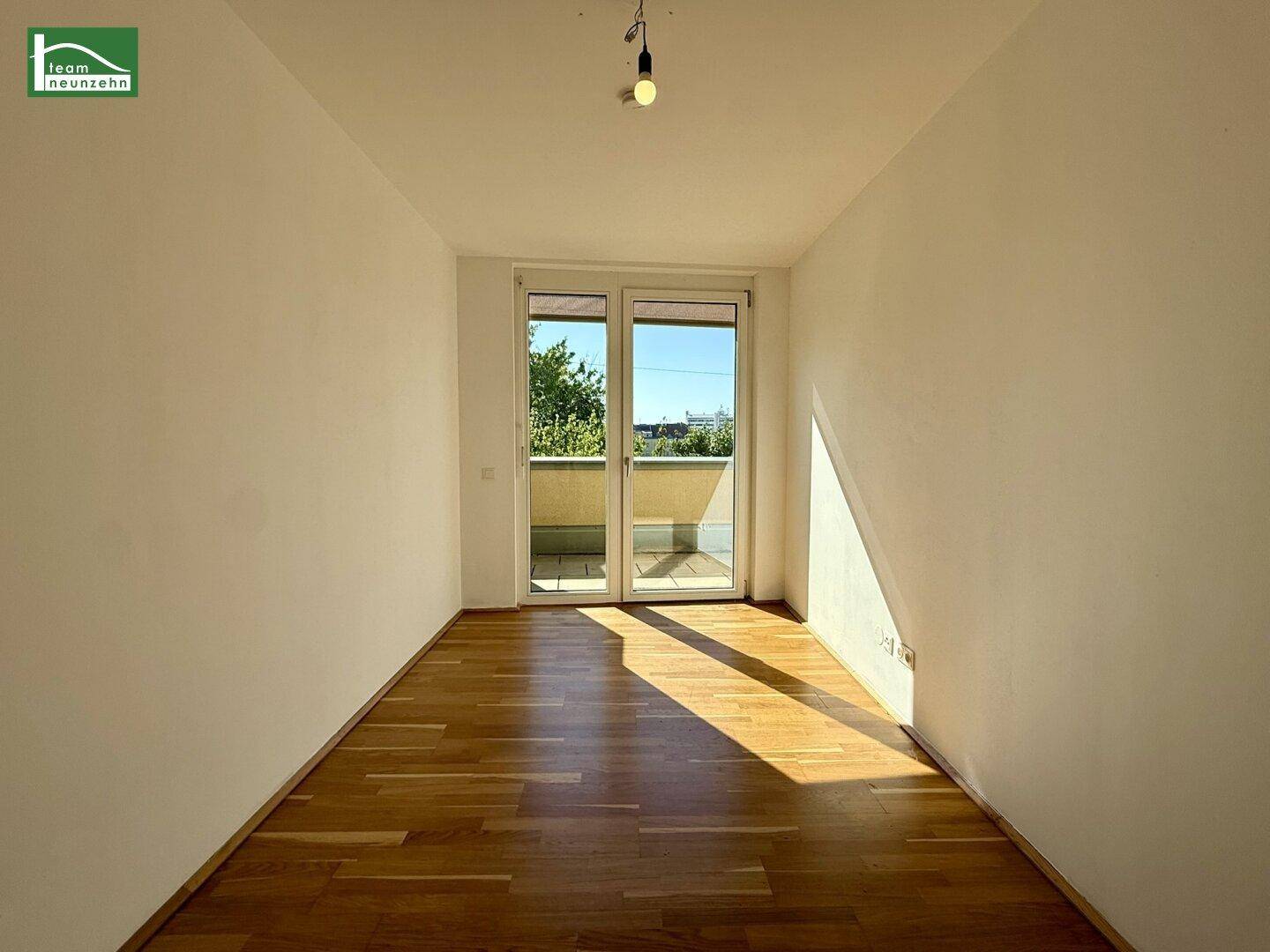Geräumiges Zimmer mit Parkettboden und Balkonzugang, ideal für flexible Einrichtung.