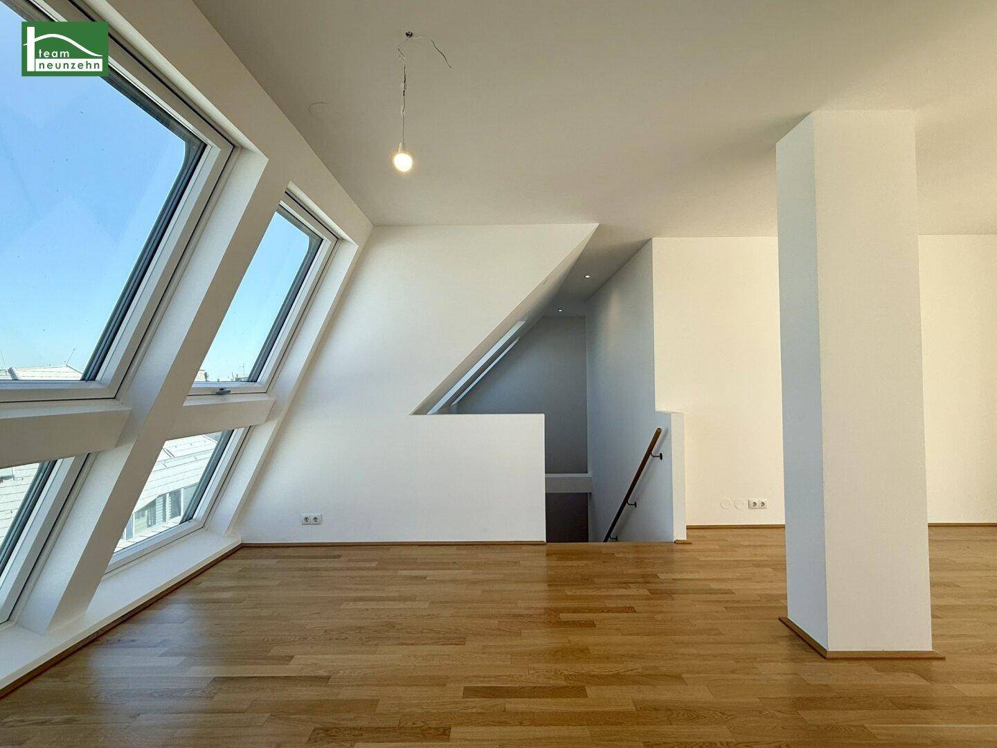 Geräumiger Wohnbereich im Dachgeschoss mit schrägen Fenstern und Holzboden, der einen offenen Grundriss andeutet.