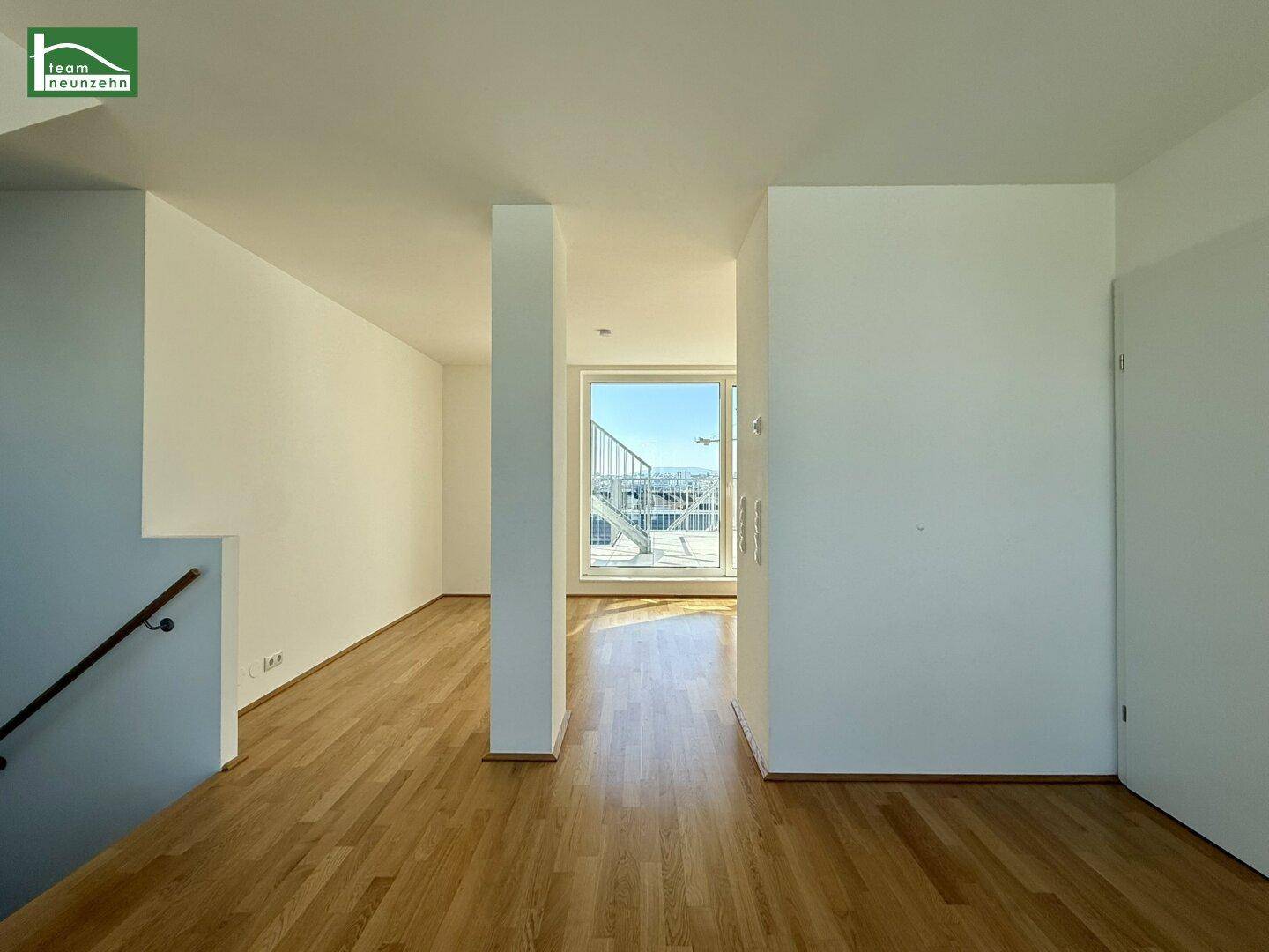 Heller Flurbereich mit Holzboden und einem Fenster am Ende, das einen Blick nach draußen ermöglicht.