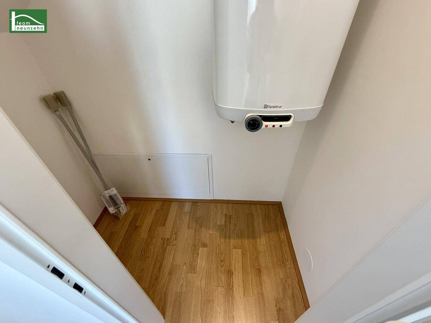 Kleiner Abstellraum mit Warmwasserboiler und Holzboden, ideal für zusätzlichen Stauraum.