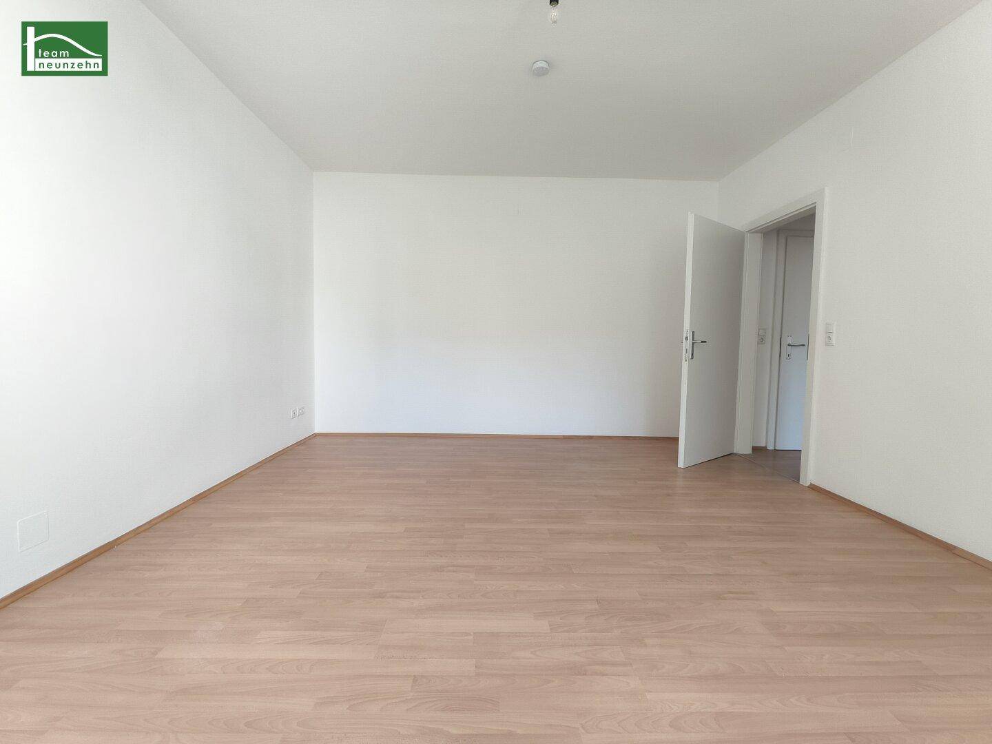 Geräumiges, unmöbliertes Zimmer mit hellem Laminatboden und weiß gestrichenen Wänden, ideal für flexible Nutzung.