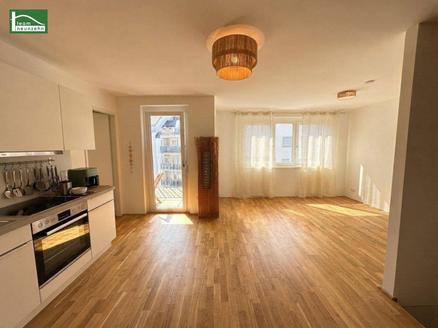 Geräumiger, heller Wohn-Essbereich mit offener Küche und direktem Zugang zum sonnigen Balkon.