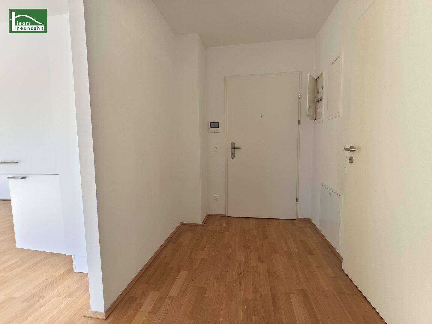 Eingangsbereich mit Holzboden und weiß gestrichenen Wänden, bietet einen klaren Zugang zu den Wohnräumen.