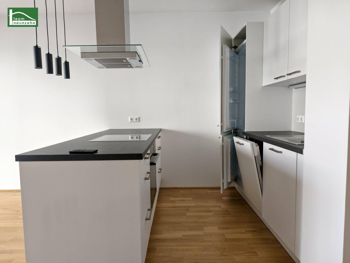Moderne Einbauküche mit Kochinsel, integrierten Geräten und dunkler Arbeitsplatte.