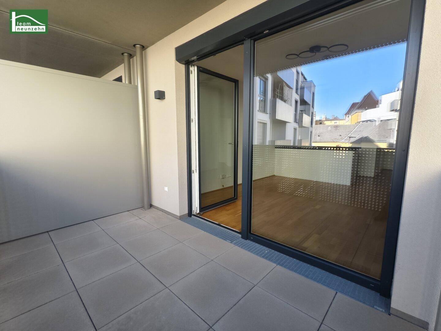 Geräumiger Balkon mit Fliesenboden und Blick auf die umliegenden Gebäude, ideal zum Entspannen.