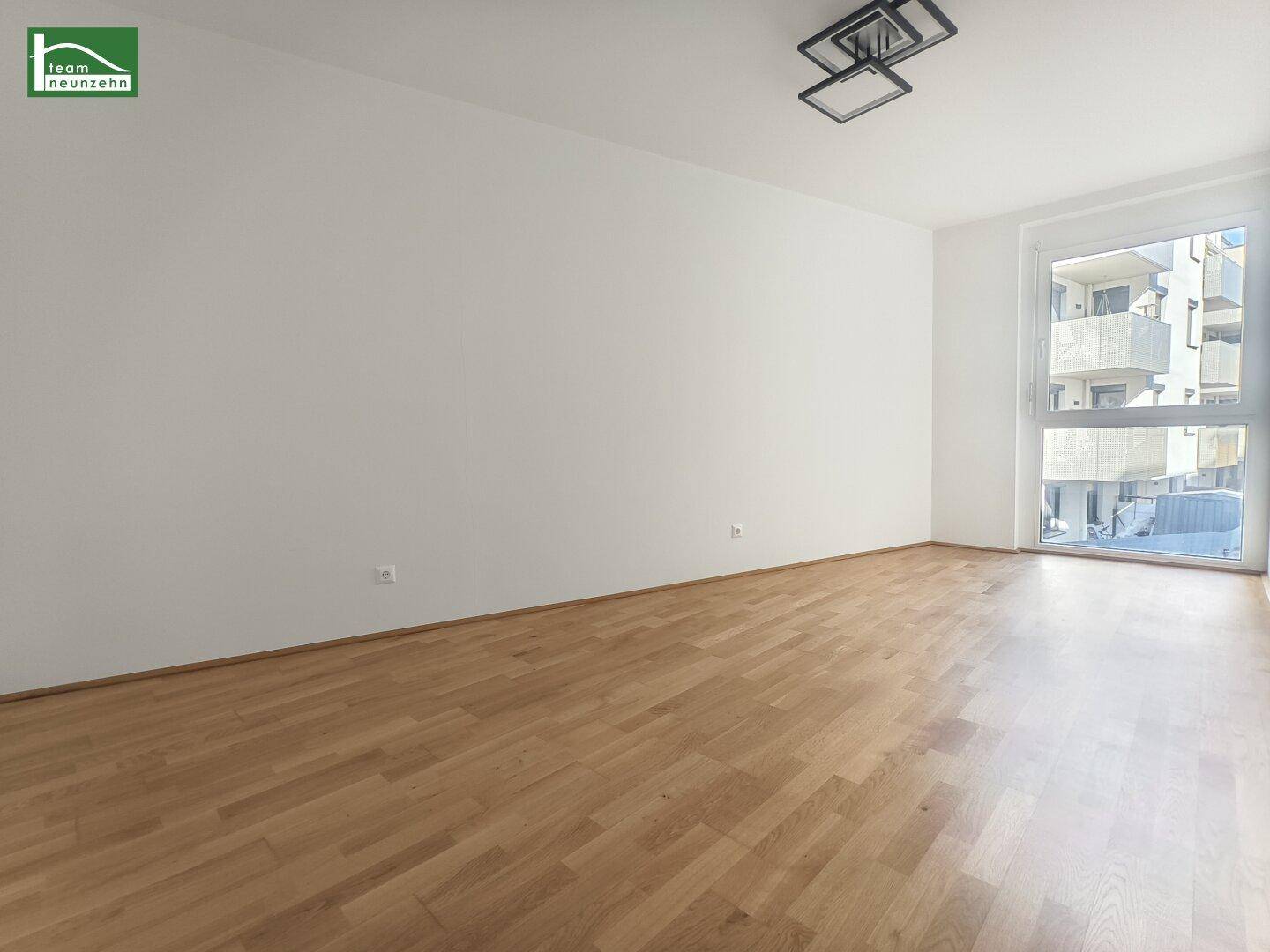 Lichtdurchflutetes Zimmer mit großem Fenster und Holzboden, bietet viel Tageslicht.