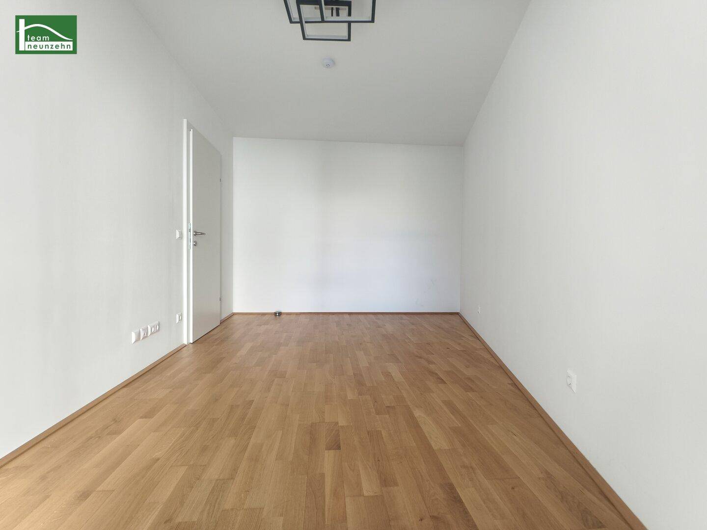 Helles, leeres Zimmer mit Parkettboden und weiß gestrichenen Wänden, bereit zur individuellen Gestaltung.