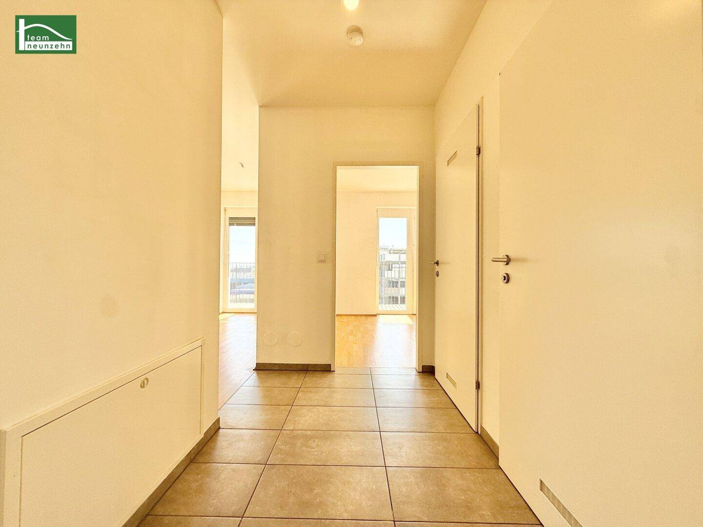 Heller Flur mit Fliesenboden und Zugang zu verschiedenen Räumen der Wohnung.