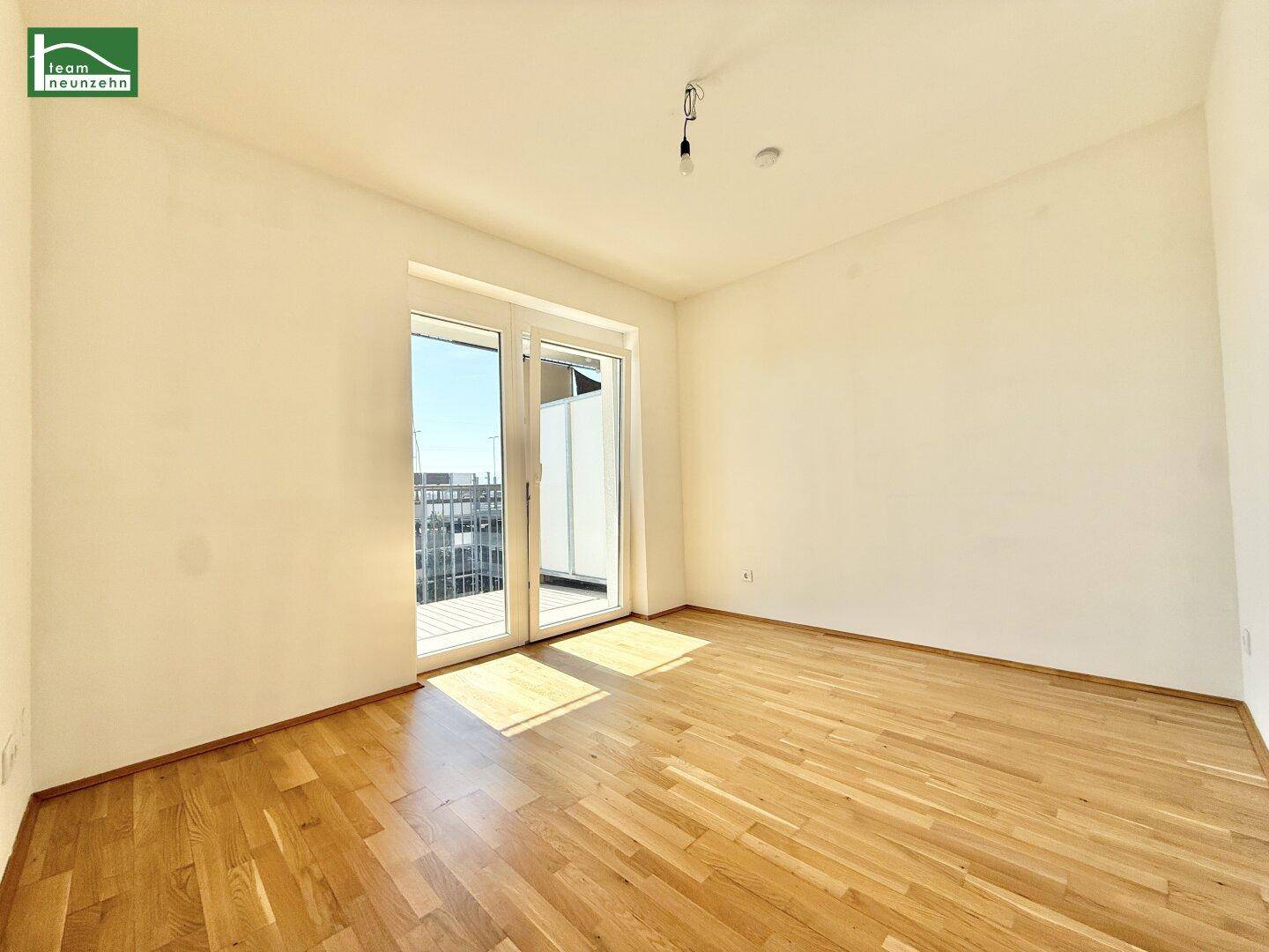 Helles Schlafzimmer mit Parkettboden und direktem Zugang zu einem Balkon.