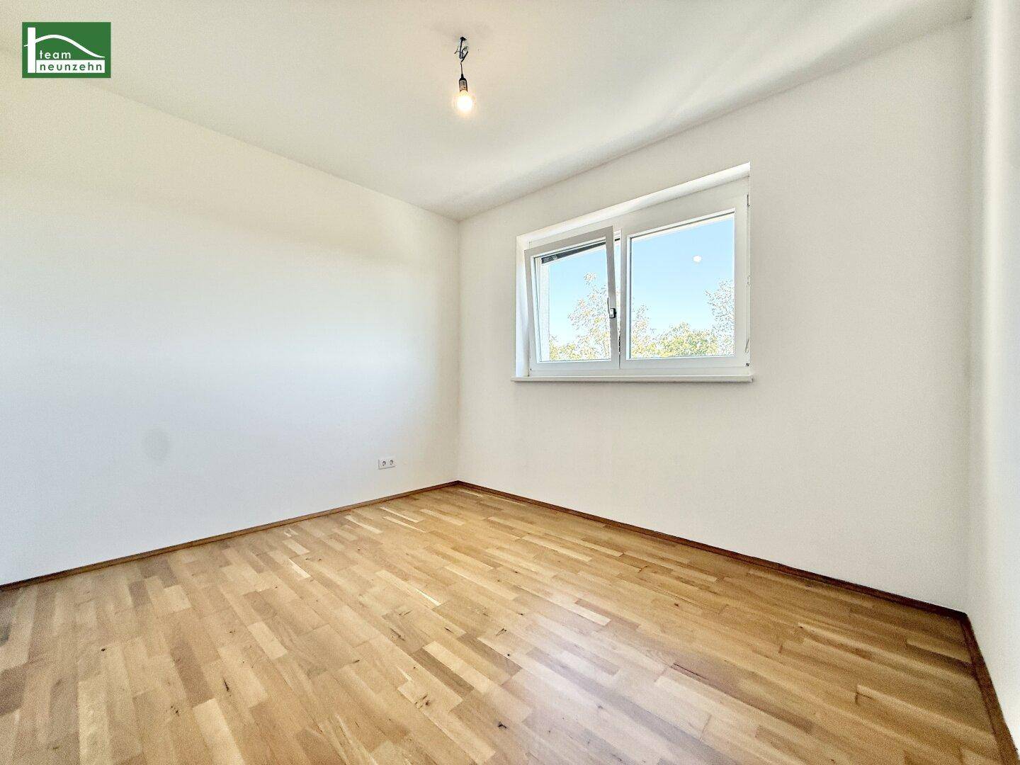 Geräumiges Schlafzimmer mit Parkettboden und einem Fenster, das viel Tageslicht spendet.
