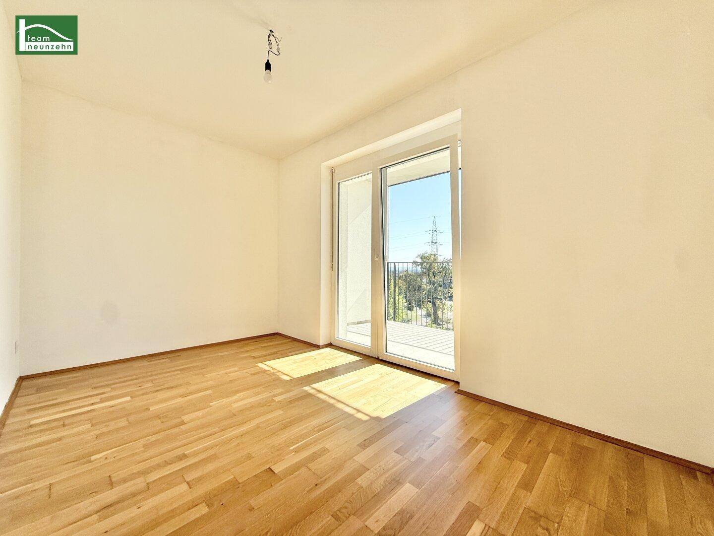 Weiteres helles Schlafzimmer mit Parkettboden und Zugang zum Balkon.