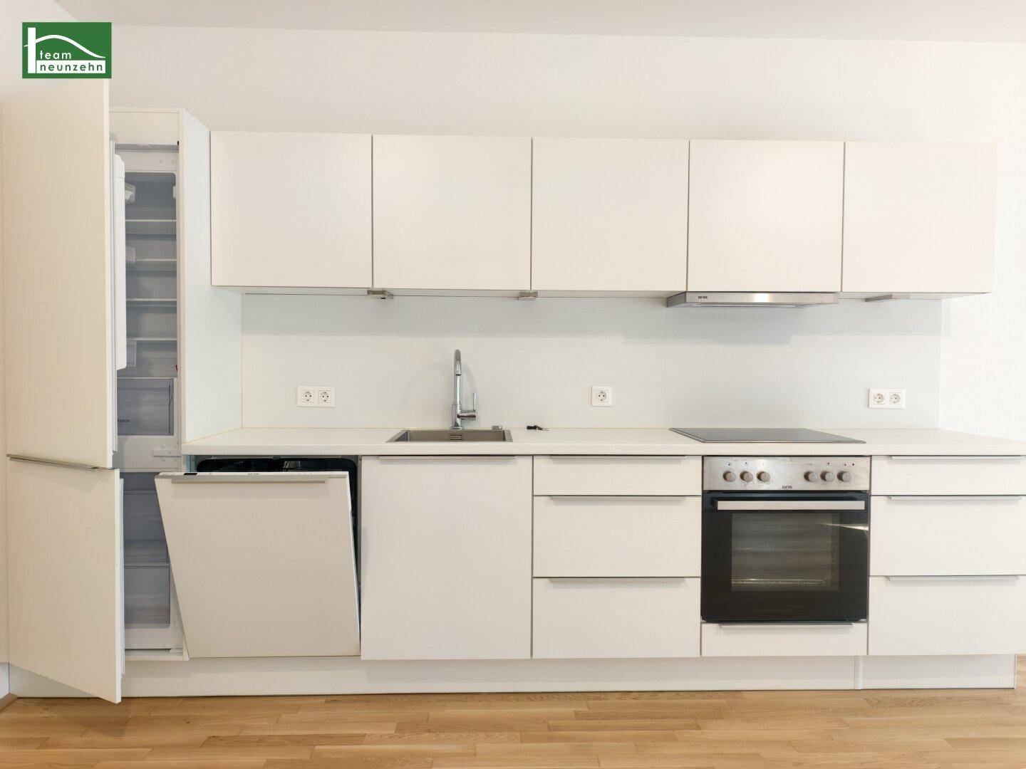 Moderne Einbauküche in Weiß mit integrierten Geräten und viel Stauraum.