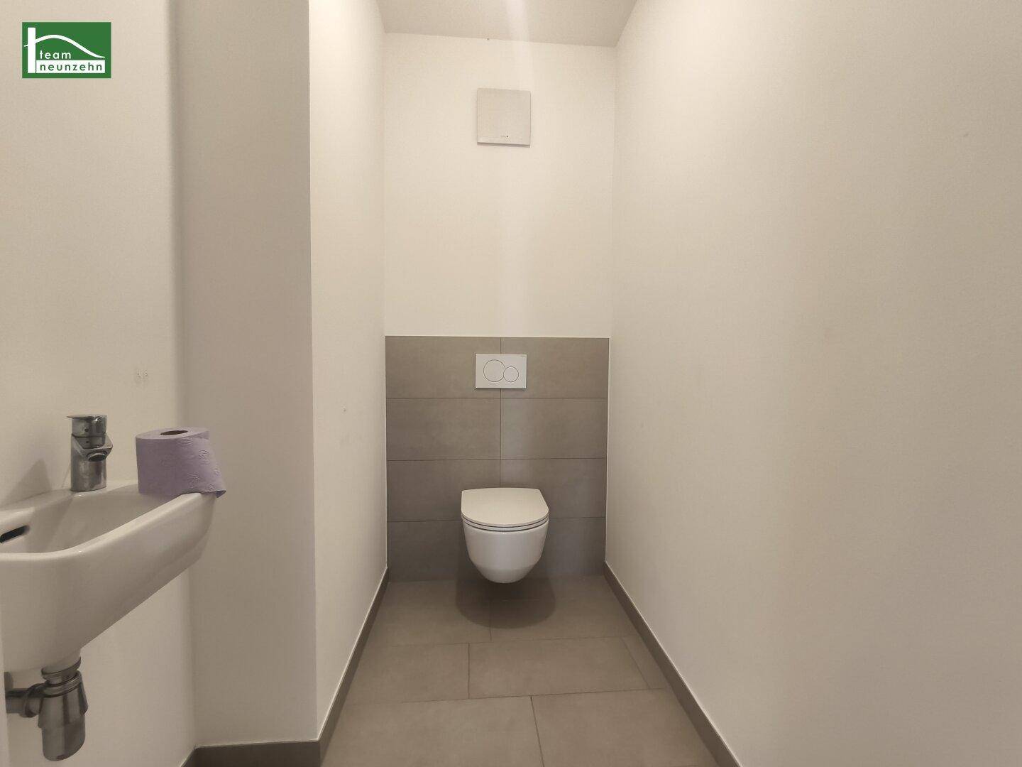 Kleines WC mit wandhängender Toilette und Handwaschbecken.