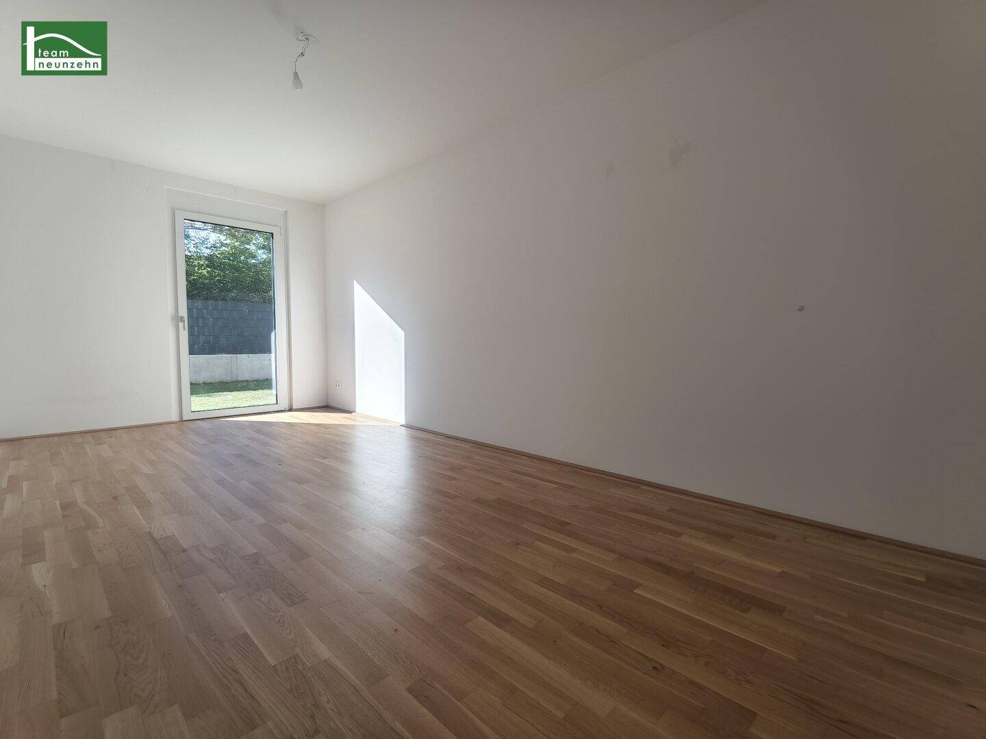 Lichtdurchfluteter Raum mit Holzboden und direktem Zugang zu einem Außenbereich.