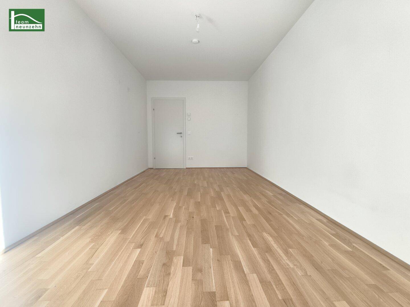 Leerer Raum mit hellem Holzboden und weißer Tür, bereit zur individuellen Gestaltung.