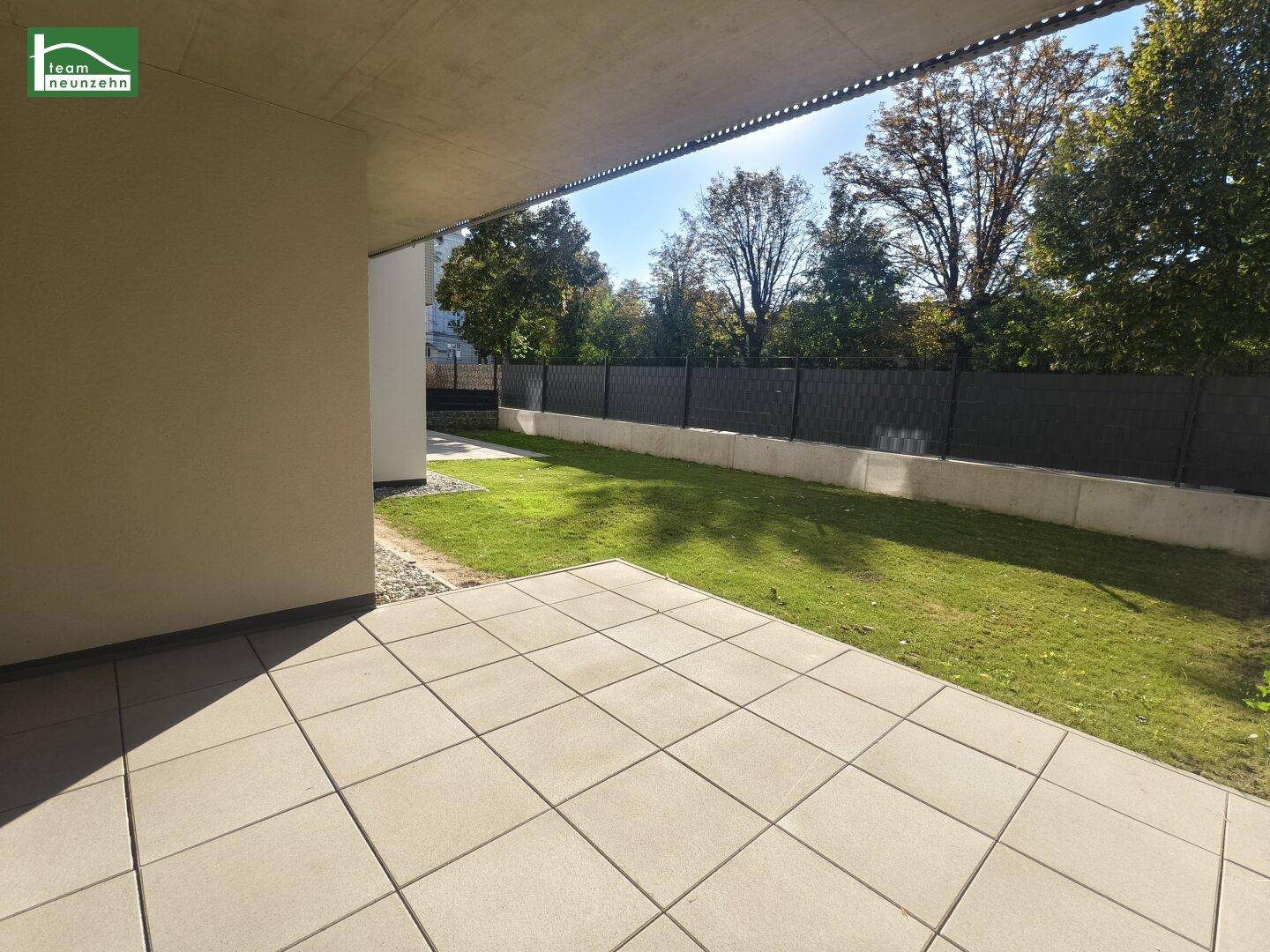 Überdachte Terrasse mit Blick auf den grünen Garten und alte Bäume.