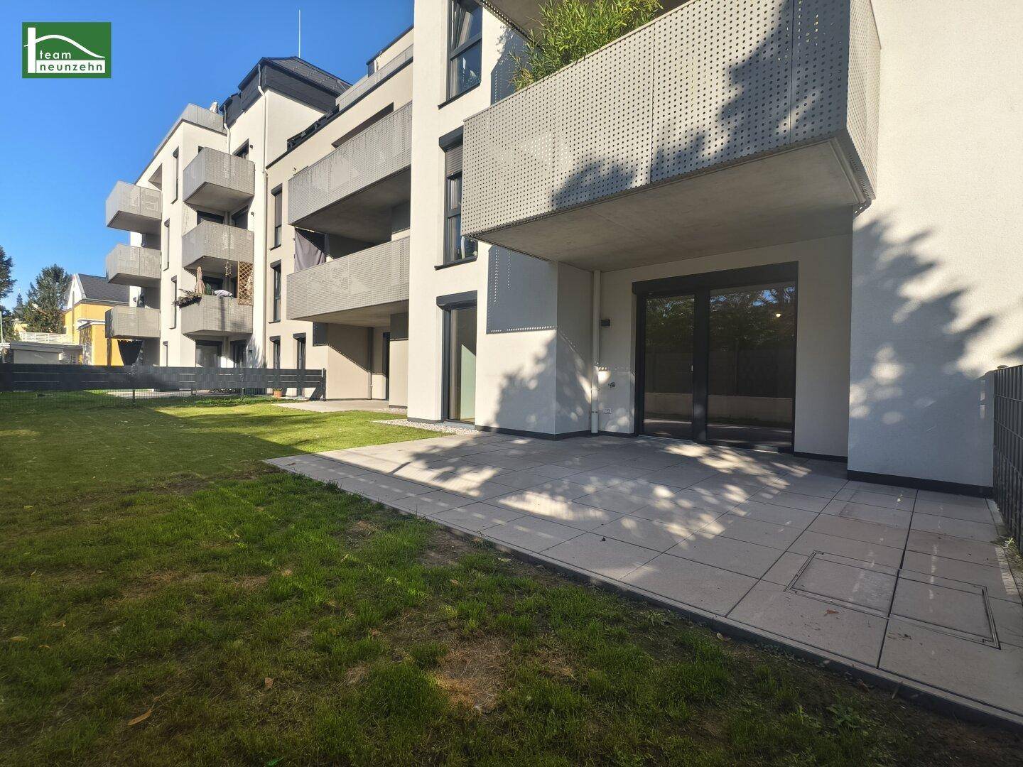 Moderner Neubau mit gepflegtem Rasen und großzügiger Terrasse im Erdgeschoss.