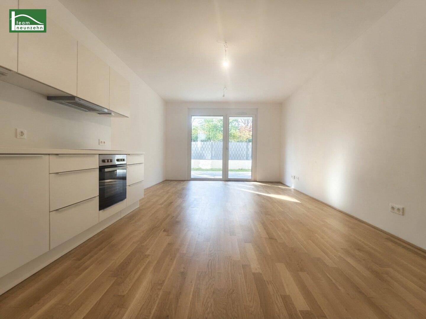 Heller Wohnbereich mit integrierter Küchenzeile, Holzboden und Zugang zum Garten.