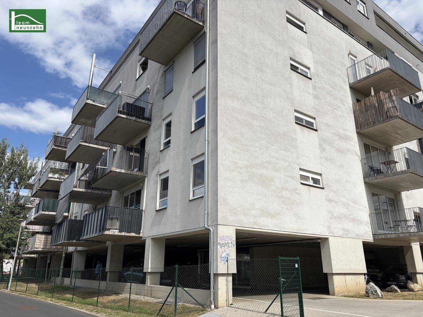 Ansicht einer modernen Wohnanlage mit zahlreichen Balkonen und einer hellen Fassade unter blauem Himmel.