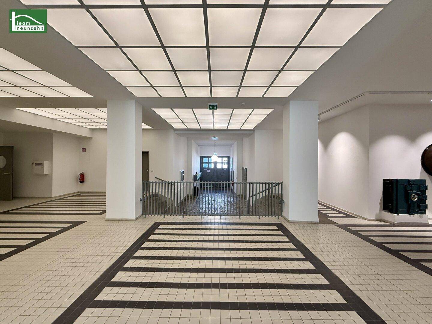 Heller und moderner Flur mit Fliesenboden und integrierter Deckenbeleuchtung in einem Gebäude.