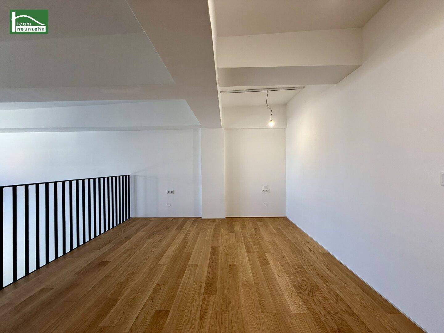 Leerer Galeriebereich mit Holzboden und modernem Geländer, ideal für Schlaf- oder Arbeitszimmer.