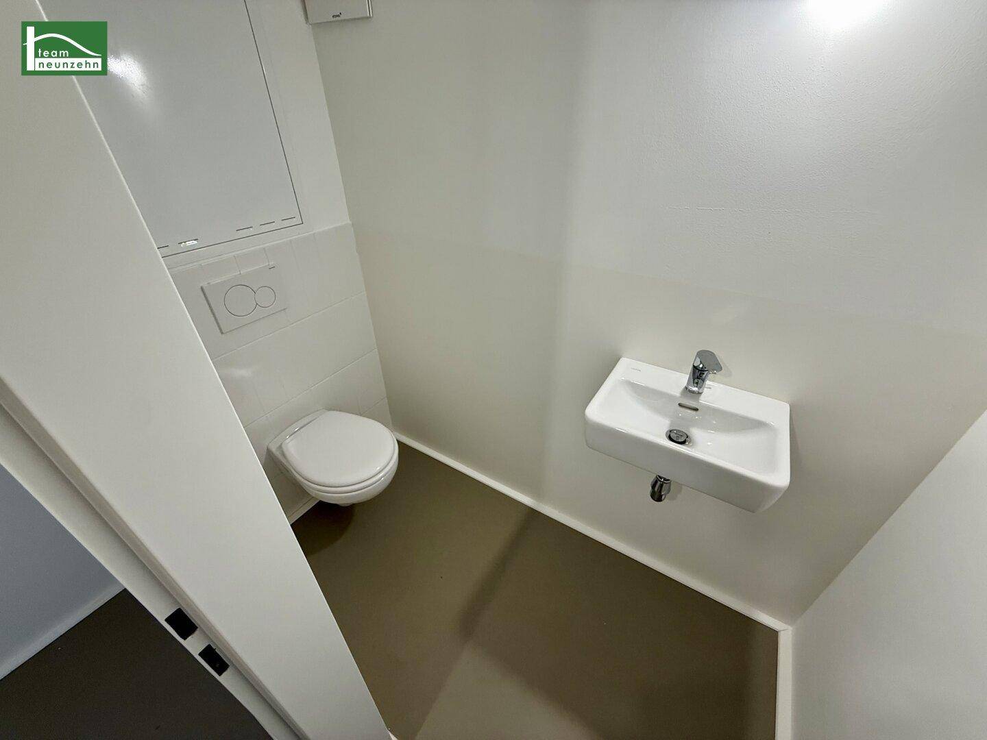 Separates WC mit Waschbecken und moderner Wandtoilette.