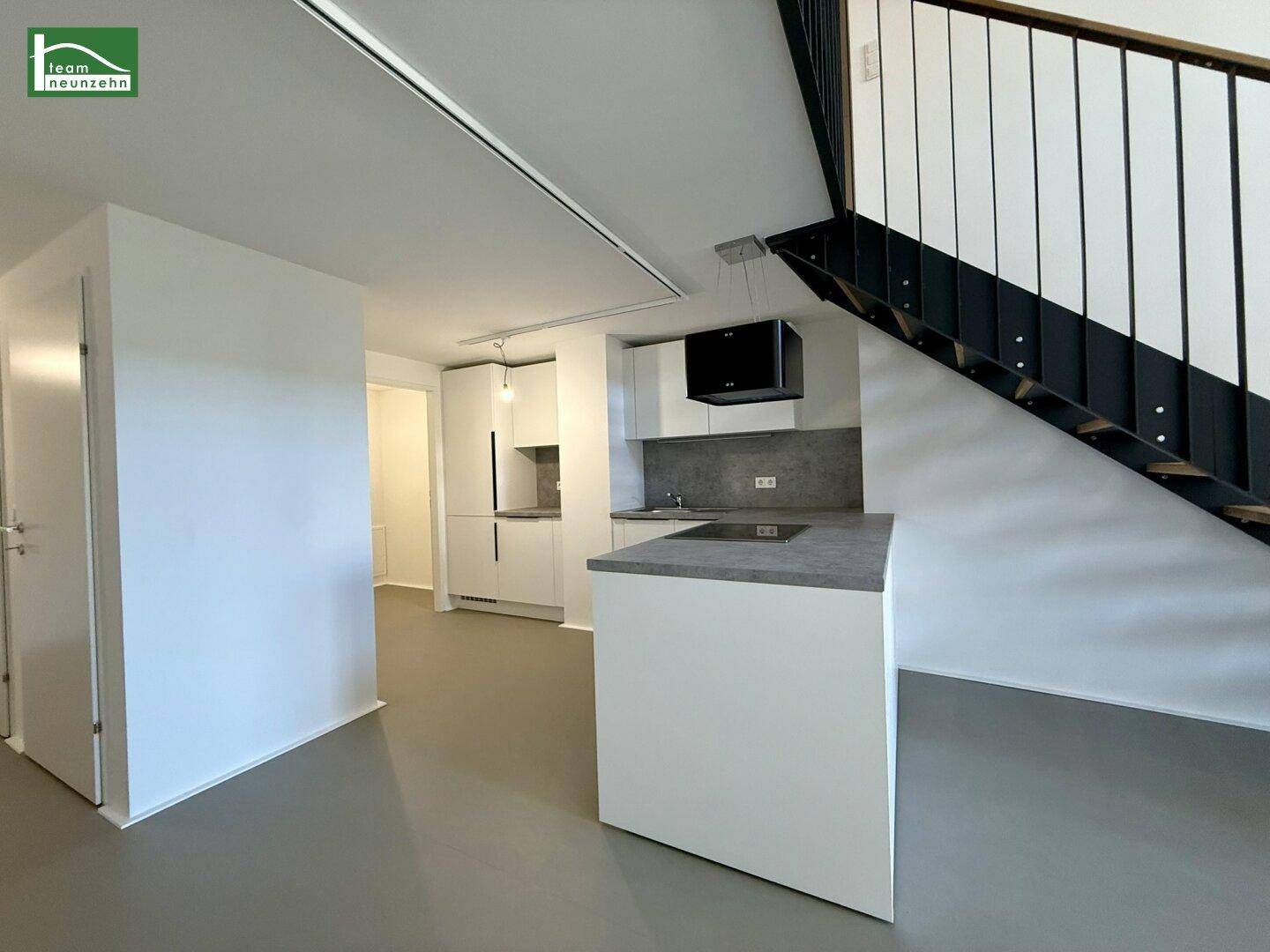 Moderne Küche mit Kochinsel, weißen Schränken und grauen Arbeitsplatten.