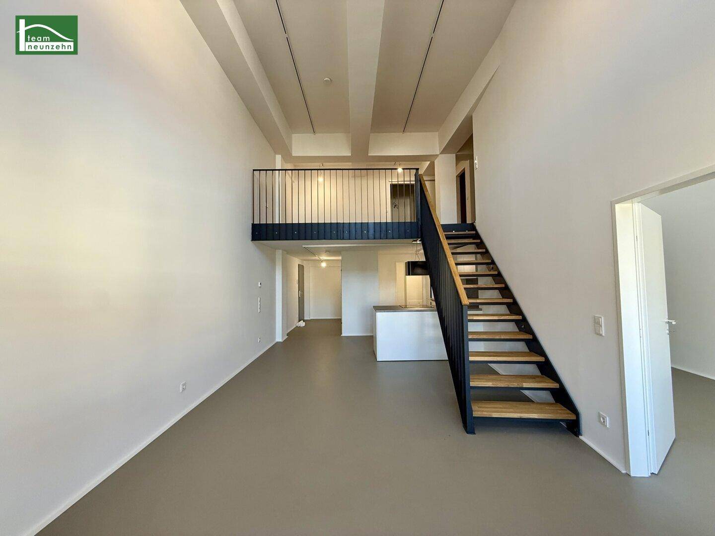 Offener Wohnbereich mit hoher Decke, Galerie und Blick auf den Küchenbereich.
