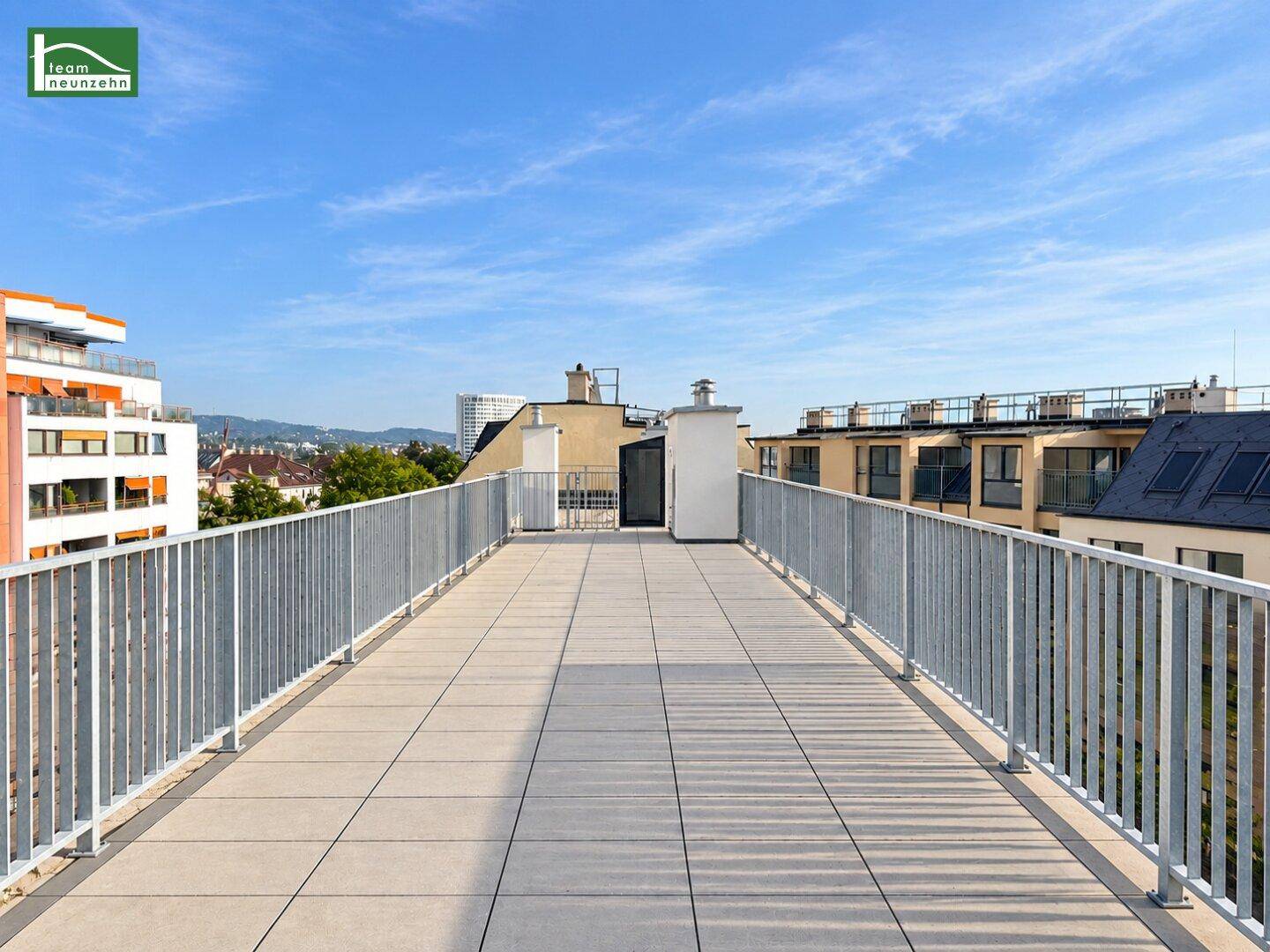 Weitläufige Dachterrasse mit Metallgeländer und Panoramablick auf die Stadtlandschaft.