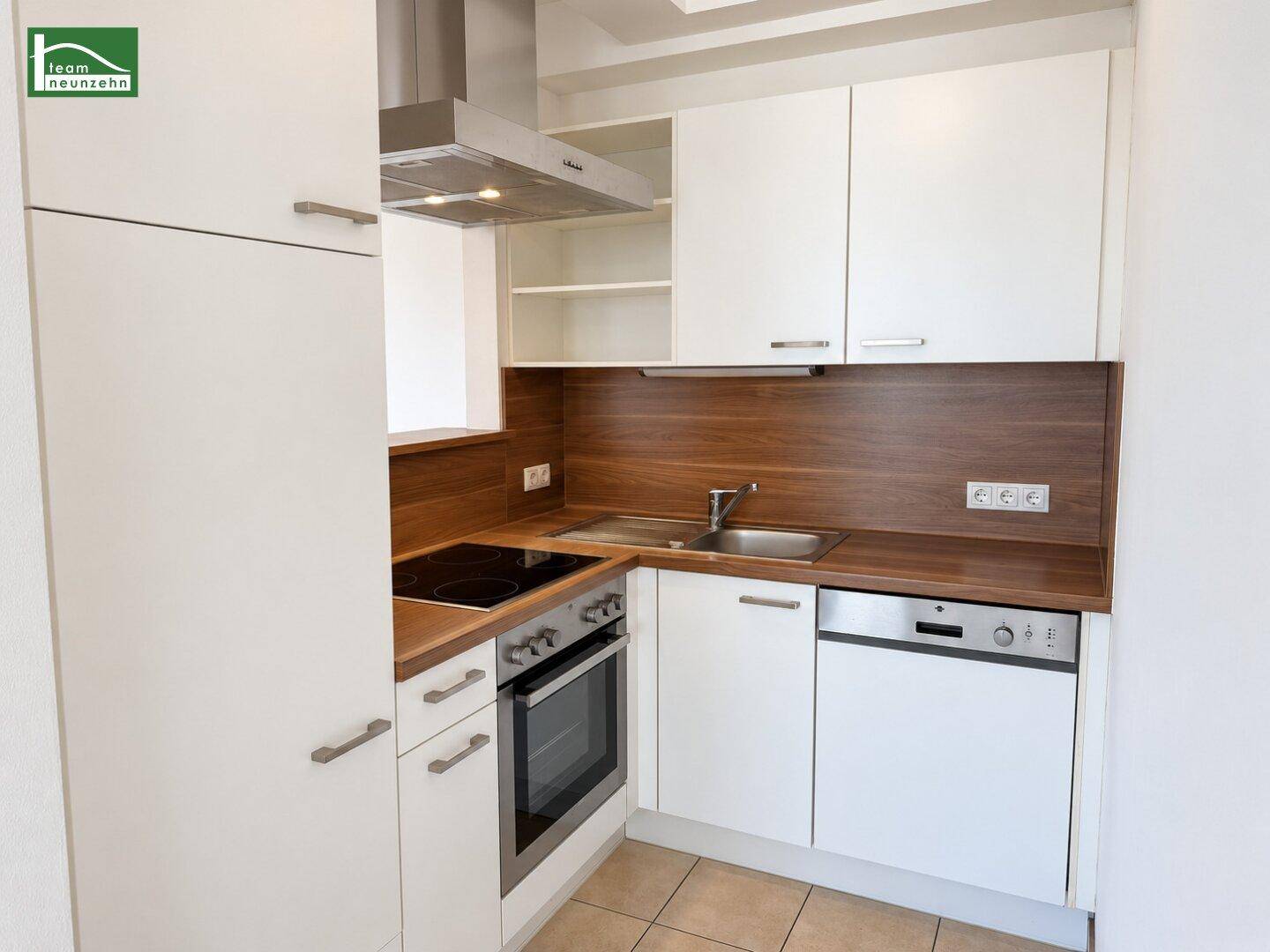 Moderne Einbauküche mit weißen Schränken, Holz-Arbeitsplatten und integrierten Geräten.