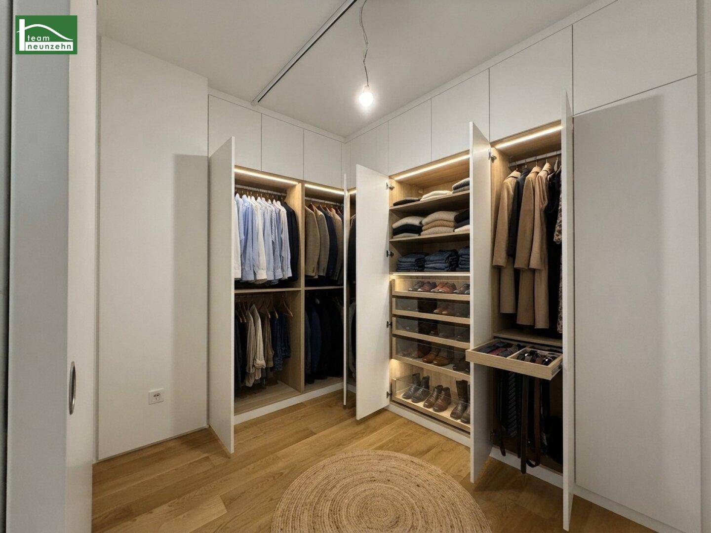 Geräumiger begehbarer Kleiderschrank mit integrierten Schränken und Holzboden.