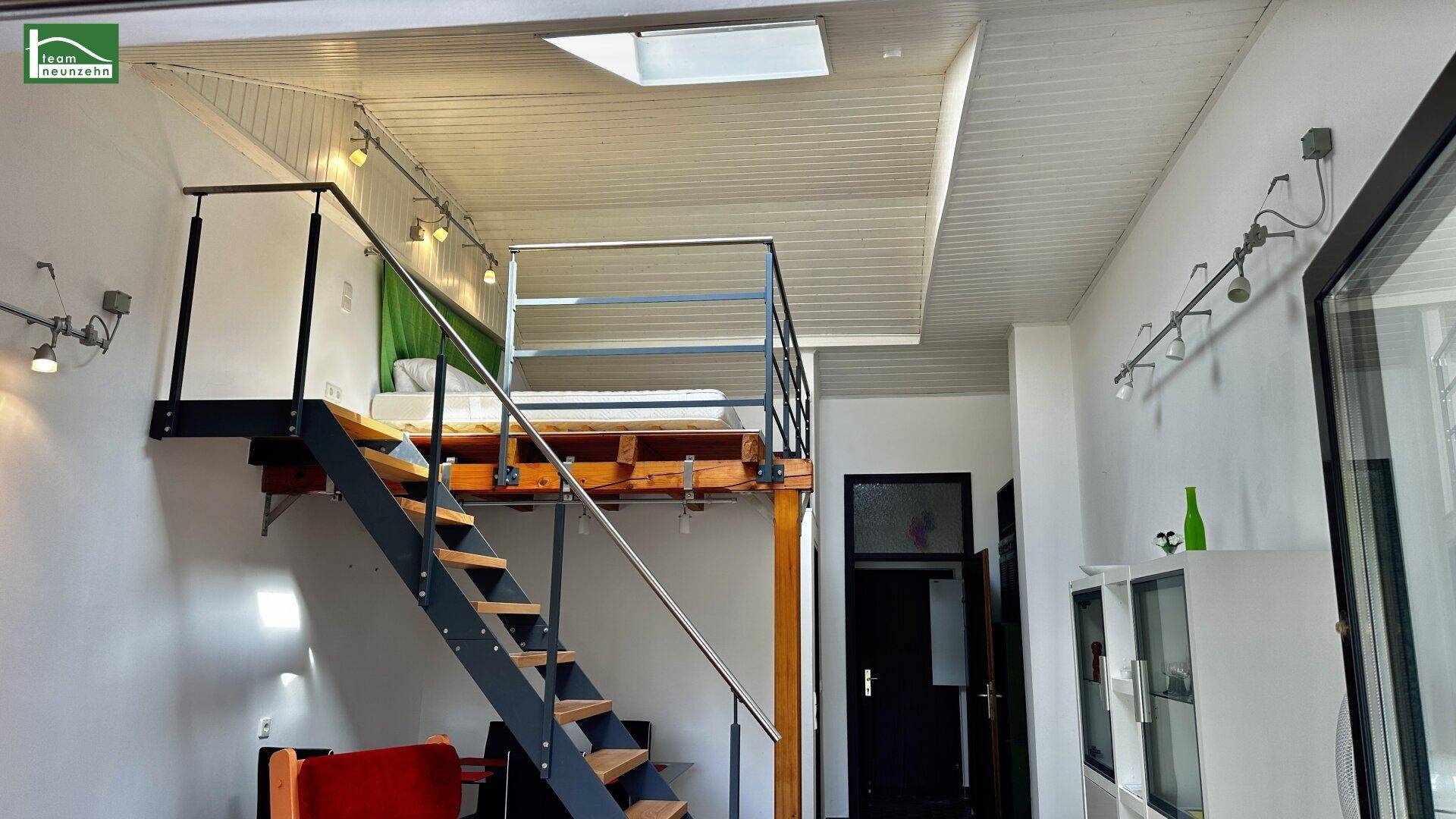 Schlafbereich auf einer Galerie mit Metallgeländer und Dachfenster, über dem Wohnbereich.