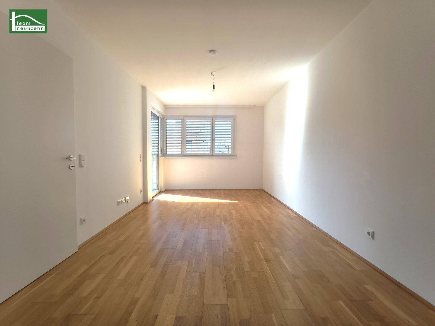 Helles Zimmer mit Holzboden und Zugang zu einem Balkon, ideal als Wohn- oder Schlafbereich.
