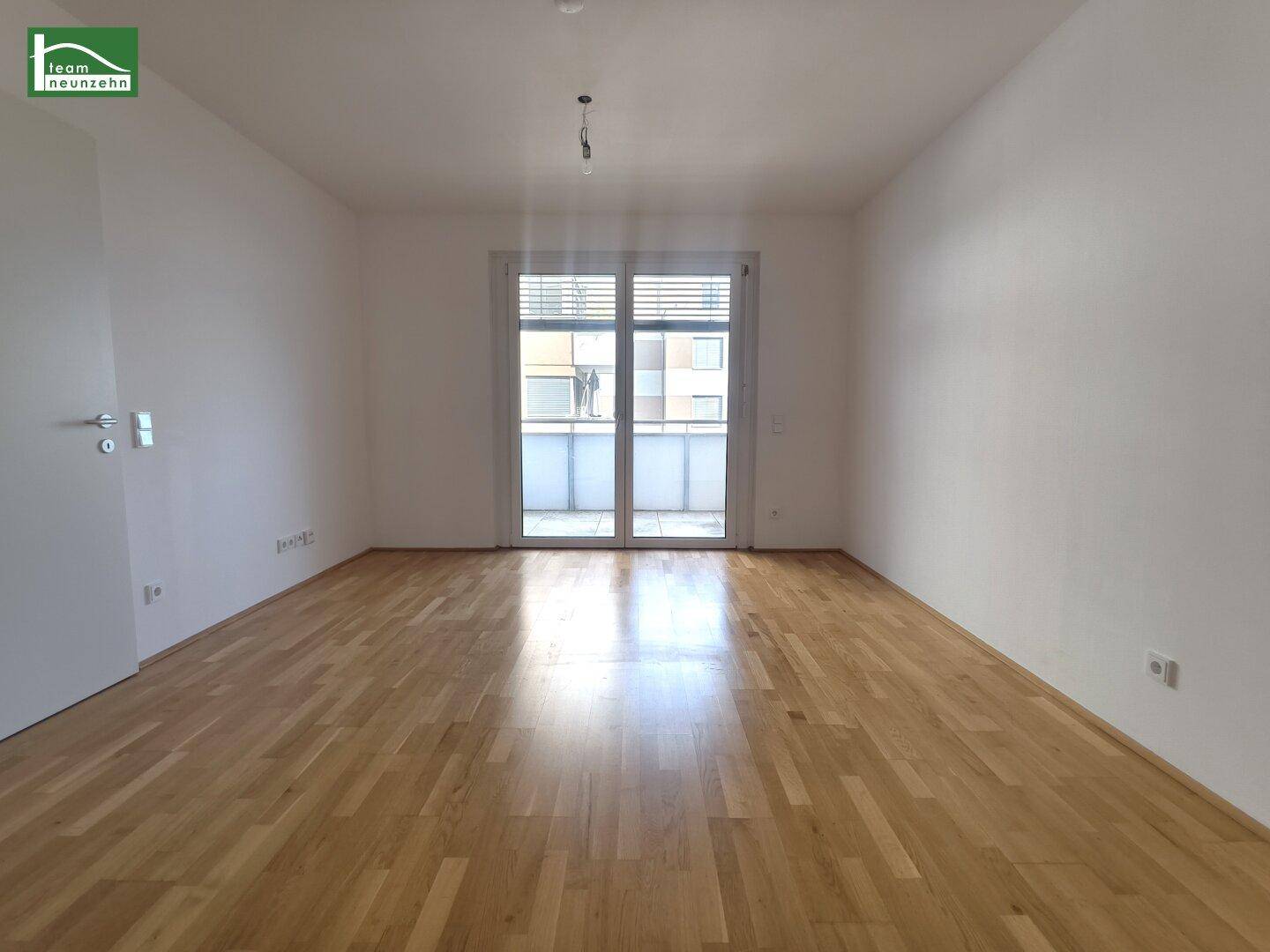 Helles Zimmer mit Parkettboden und Zugang zu einem Balkon, ideal als Wohn- oder Schlafbereich.