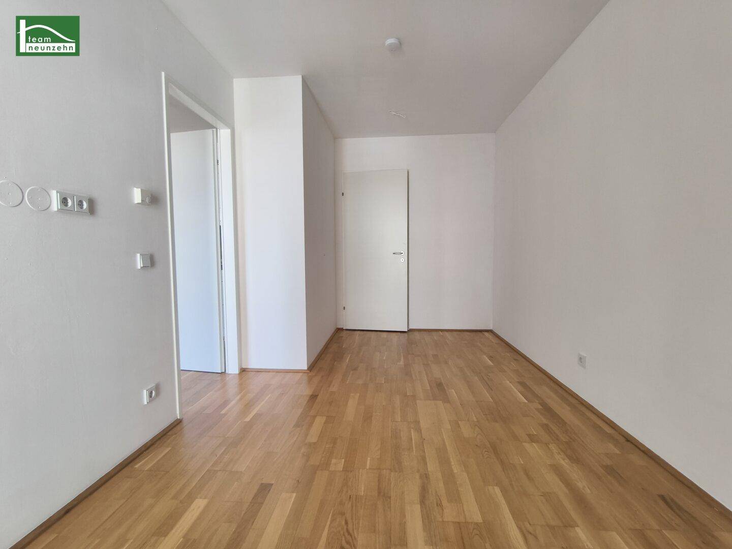 Leerer Raum mit hellem Parkettboden und weißen Wänden, bereit zur individuellen Gestaltung.