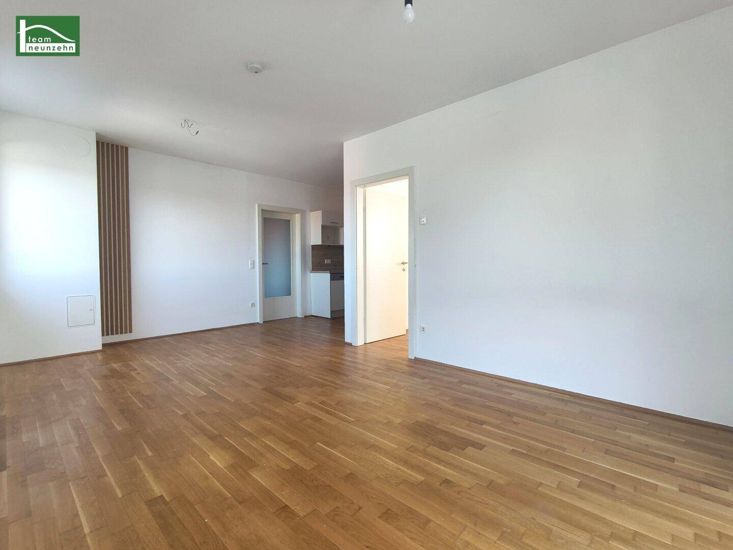 Geräumiger Wohnbereich mit hellem Parkettboden und Zugang zu weiteren Räumen.