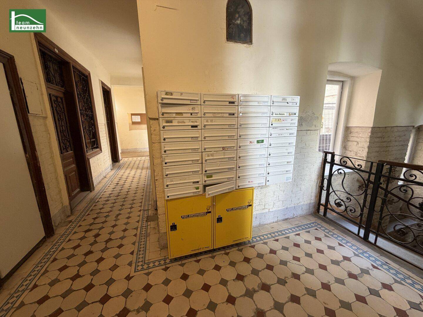 Eingangsbereich eines Mehrfamilienhauses mit Briefkästen und historischem Fliesenboden.