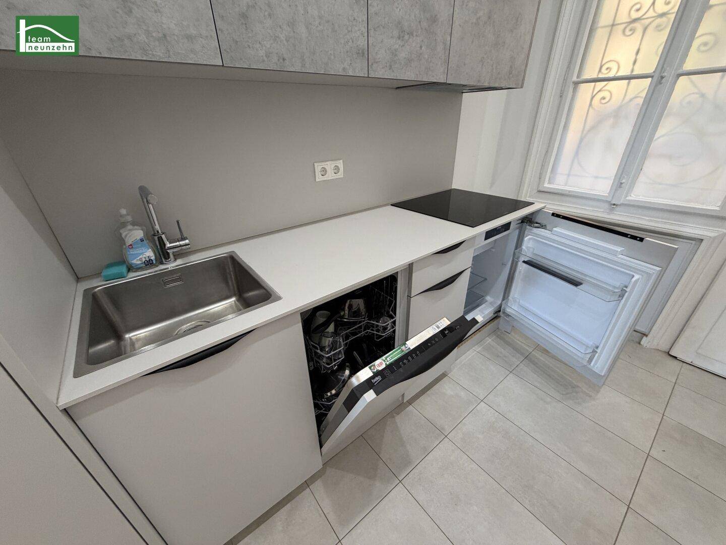 Moderne Küchenzeile mit Spüle, Kochfeld, Geschirrspüler und Kühlschrank, alles kompakt angeordnet.