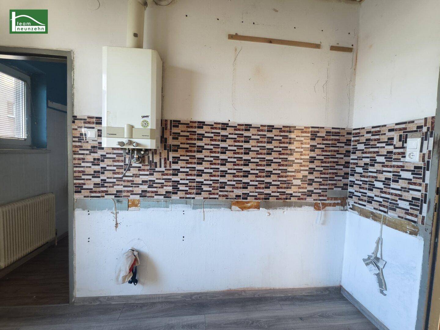 Detailansicht einer leeren Küche mit dekorativer Fliesenrückwand und Gastherme.