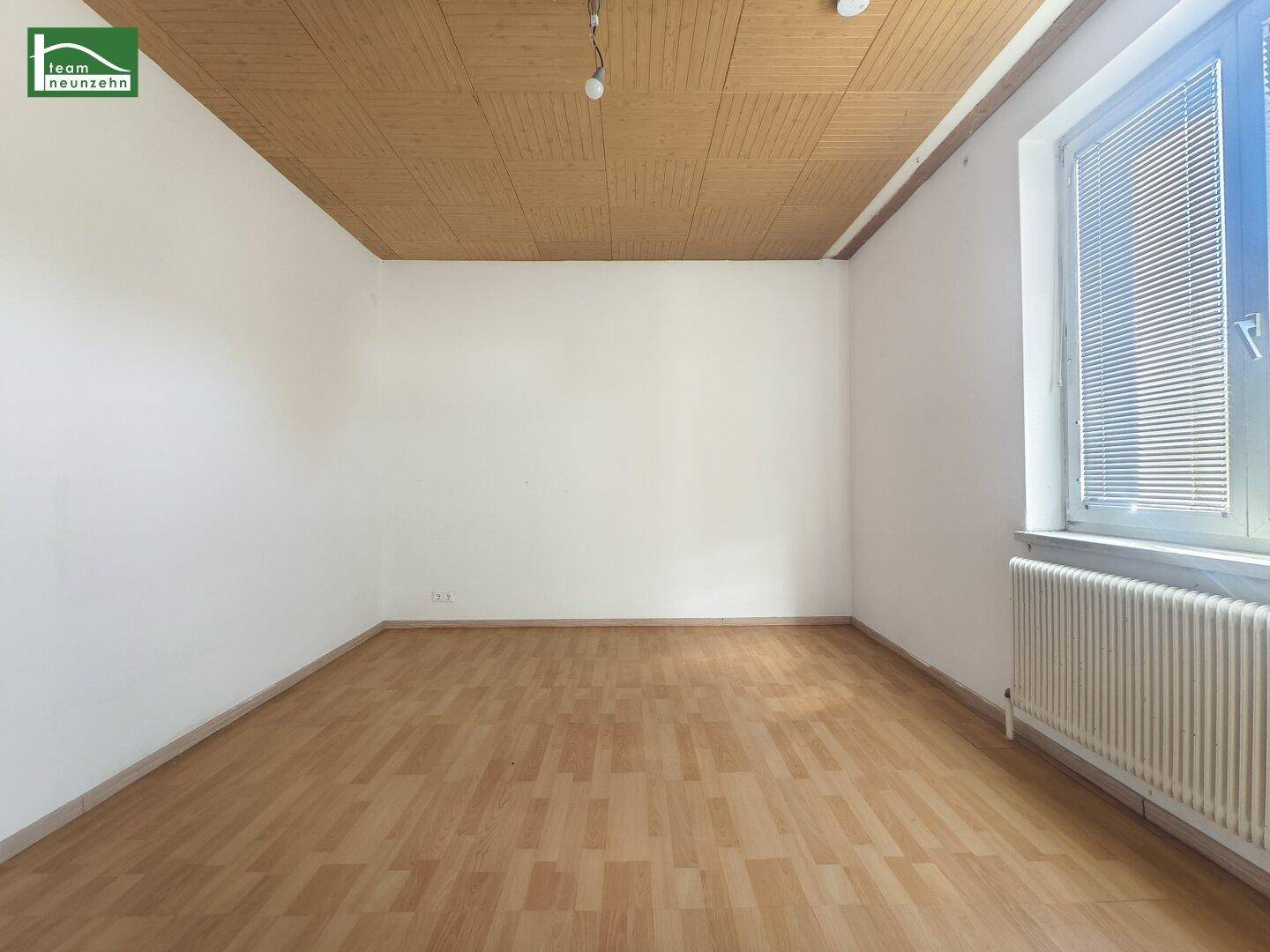 Leeres Zimmer mit Parkettboden und einer Holzpaneeldecke.