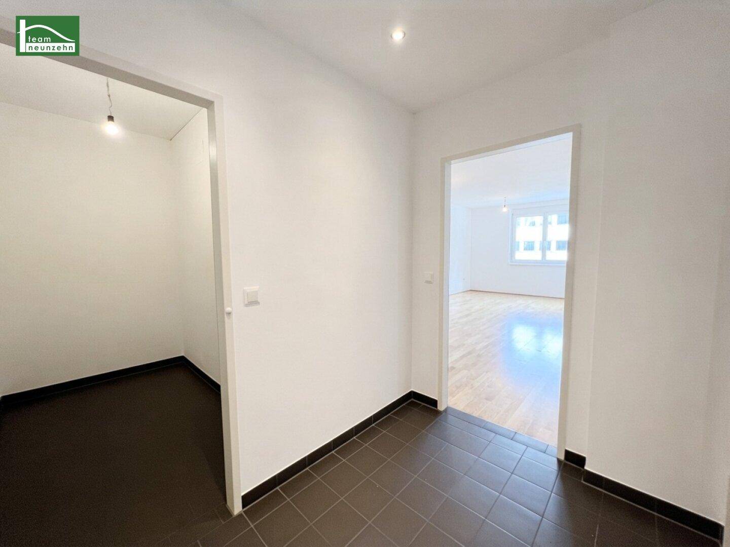 Heller Flur mit dunklem Fliesenboden, der zu den verschiedenen Zimmern der Wohnung führt.