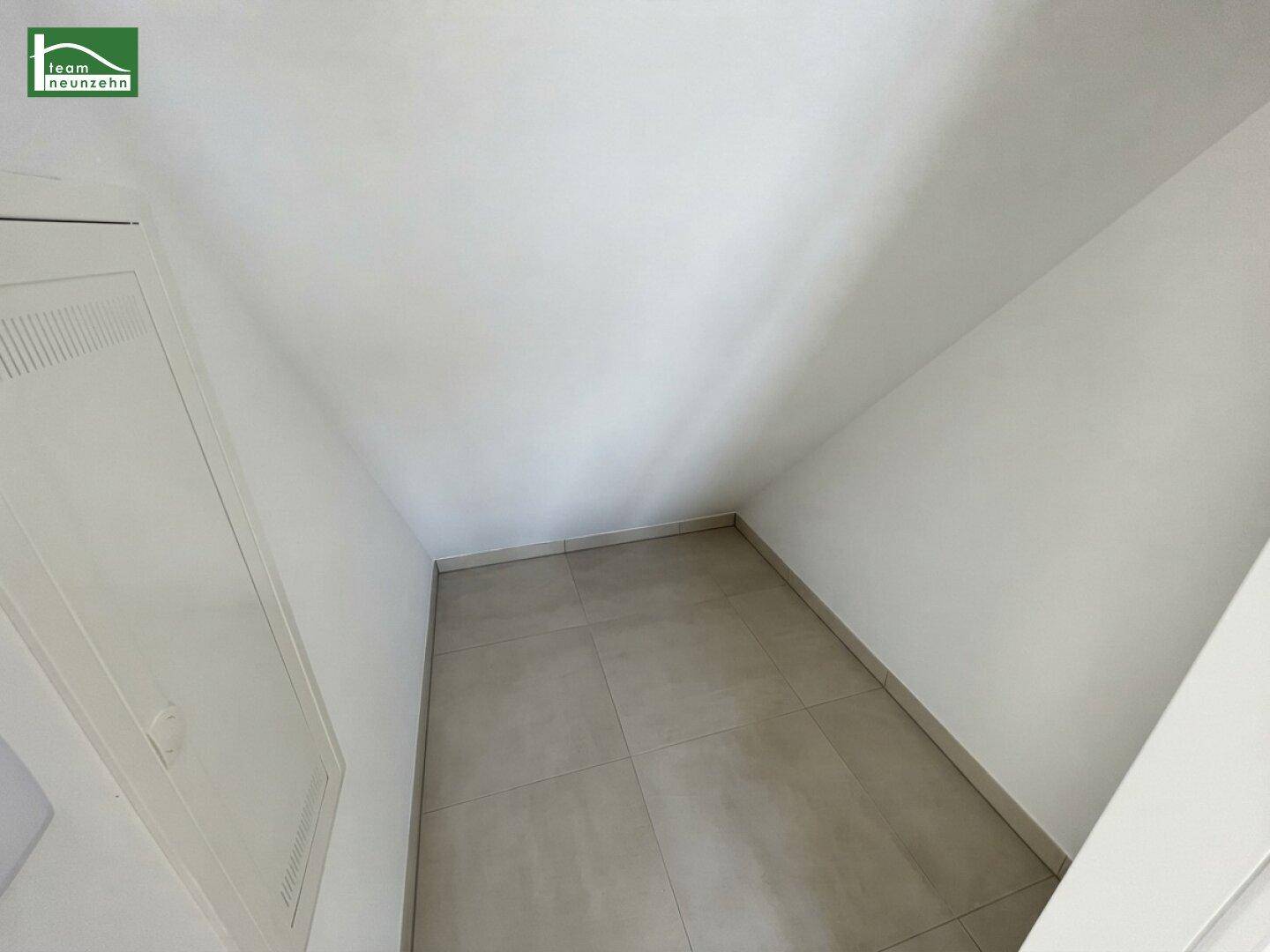 Kleiner Abstellraum mit Fliesenboden und schrägen Wänden im Dachgeschoss.