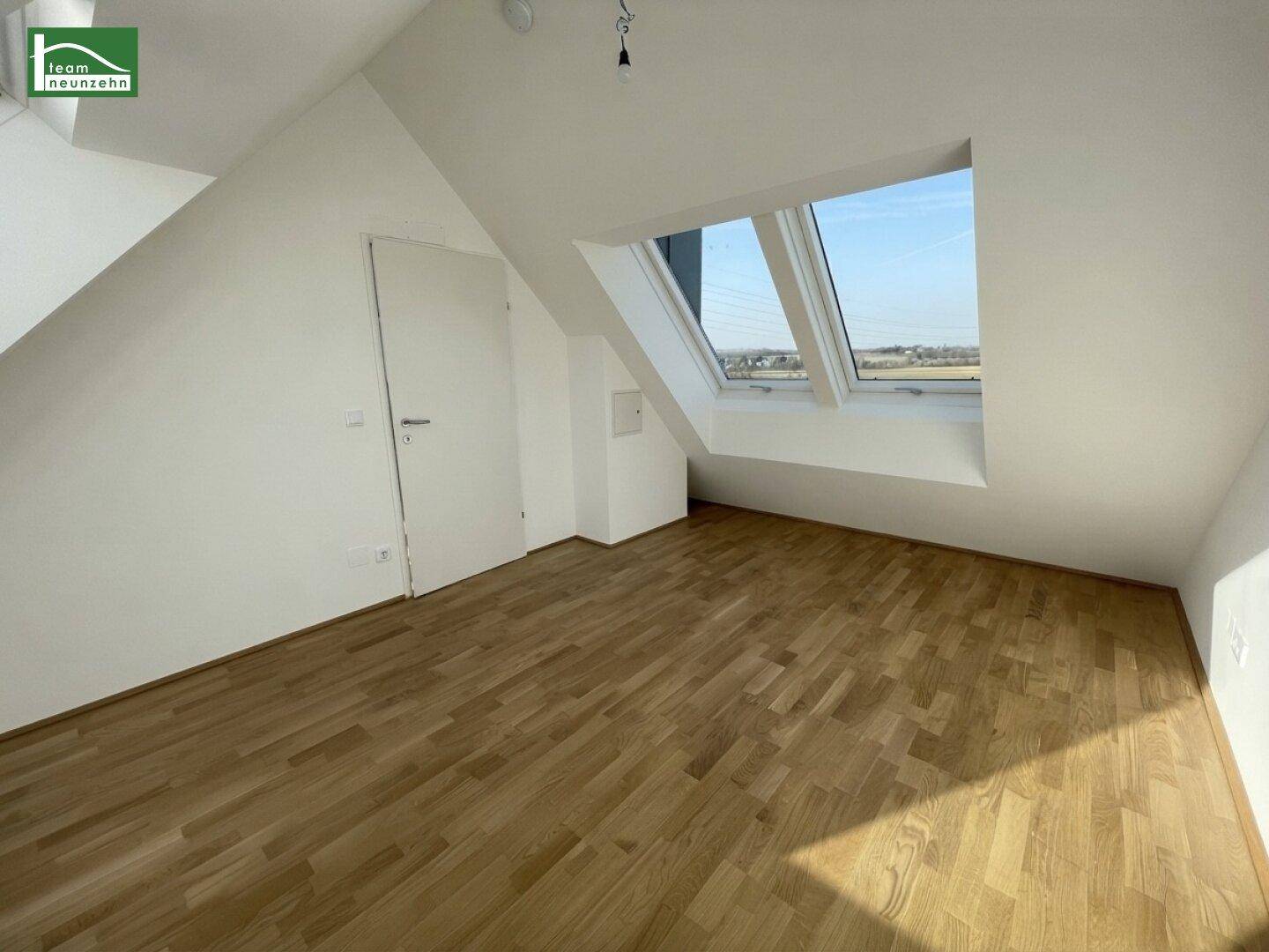 Helles Schlafzimmer im Dachgeschoss mit Holzboden, schrägen Wänden und Dachfenstern.