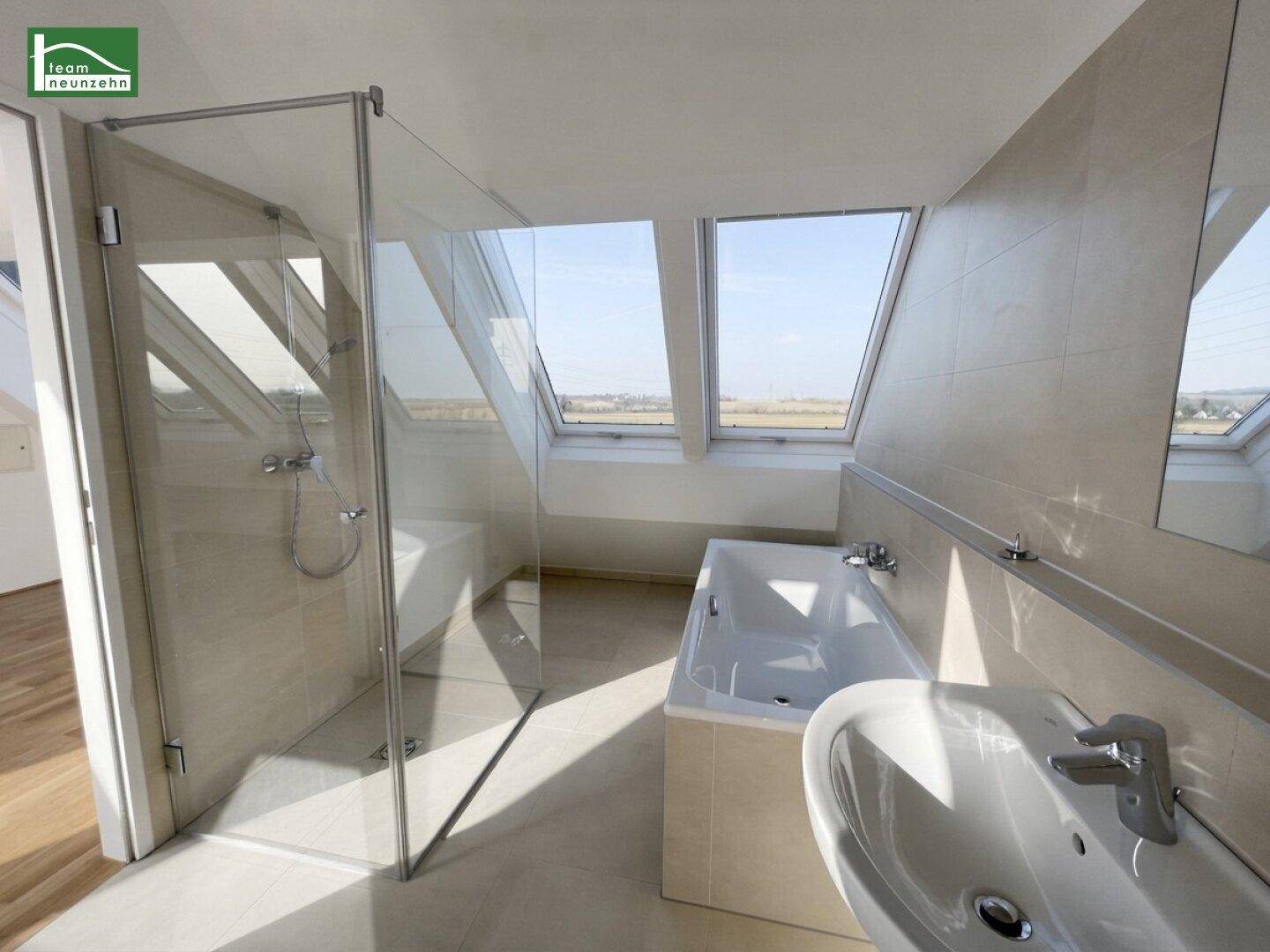 Modernes Badezimmer mit Badewanne, Dusche und Dachfenstern für viel Tageslicht.