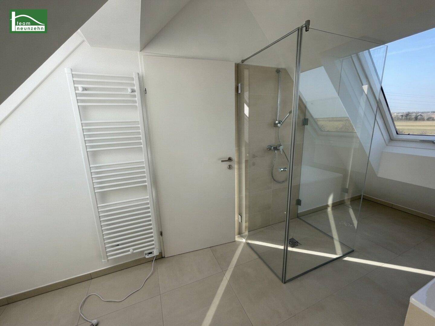 Modernes Badezimmer mit Glasdusche, Handtuchheizkörper und Fliesenboden.