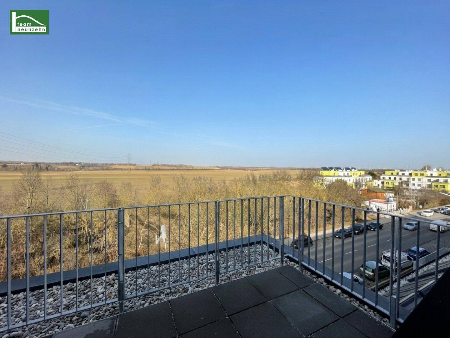 Balkon mit Ausblick auf weite Felder, eine Straße und die umliegende Landschaft.