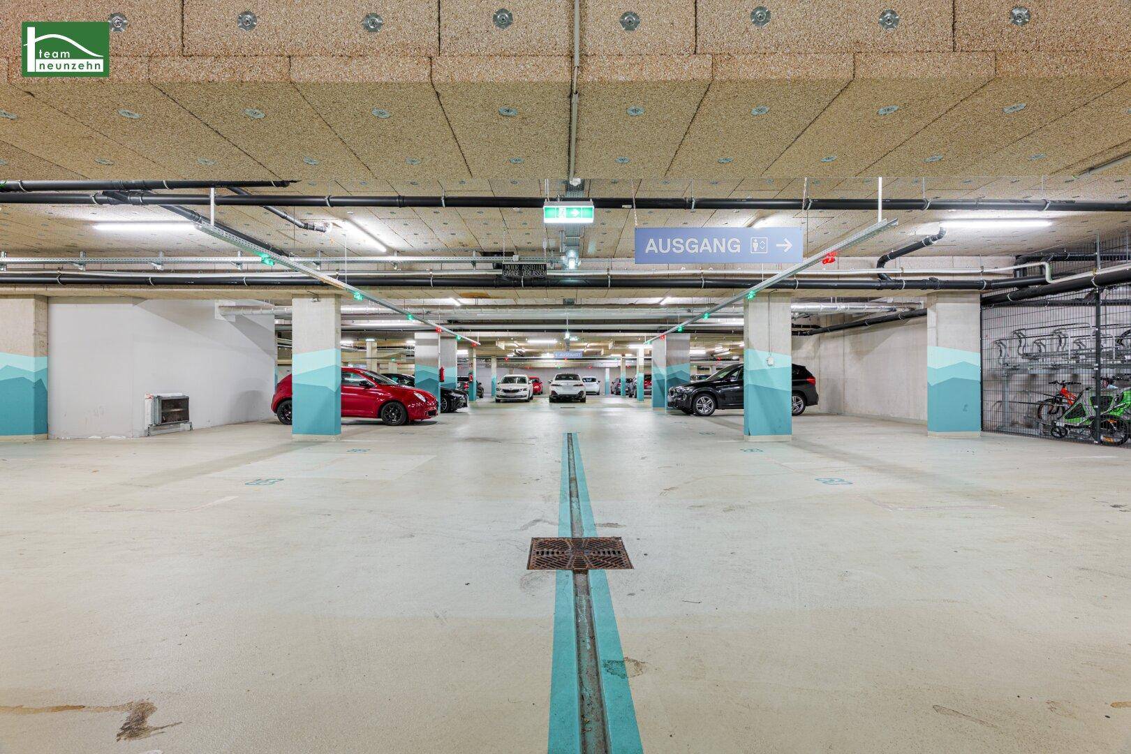 Geräumige Tiefgarage mit markierten Parkplätzen und klarer Beschilderung für den Ausgang.