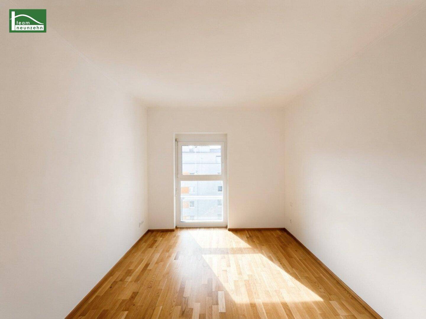 Freundliches Zimmer mit Parkettboden und einem großen Fenster für viel Helligkeit.
